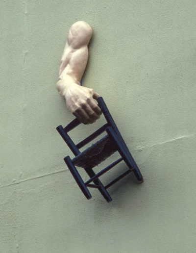 Arm hanging from a wall holding a chair